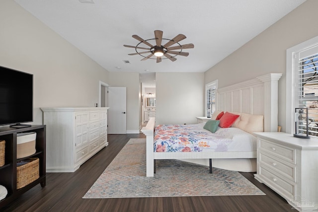 bedroom featuring dark wood-style floors, ensuite bath, and a ceiling fan