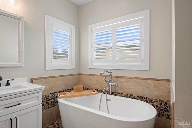 bathroom featuring a freestanding bath, wainscoting, vanity, and tile walls