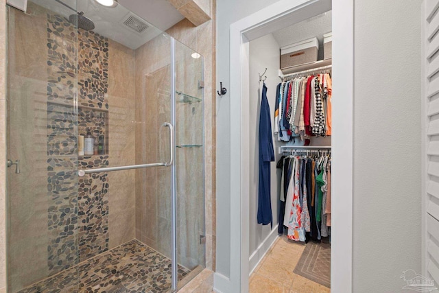 bathroom with a shower stall, a spacious closet, and visible vents