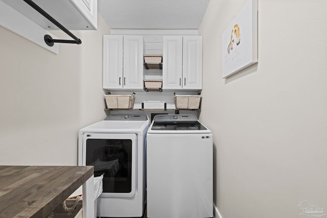 laundry area with cabinet space, a textured ceiling, and washing machine and clothes dryer