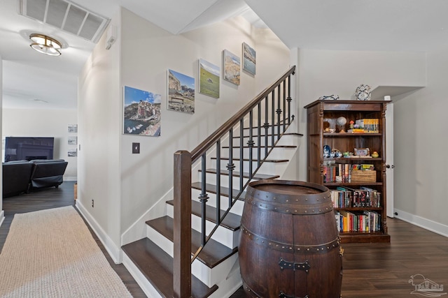 staircase featuring baseboards, visible vents, and wood finished floors