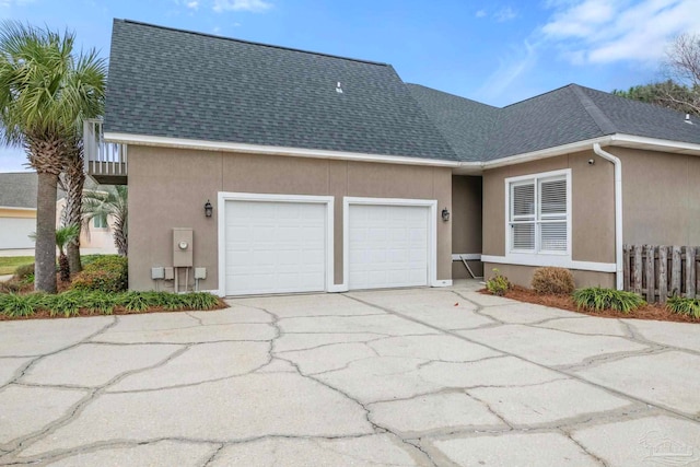 view of front facade featuring concrete driveway, a shingled roof, an attached garage, and stucco siding