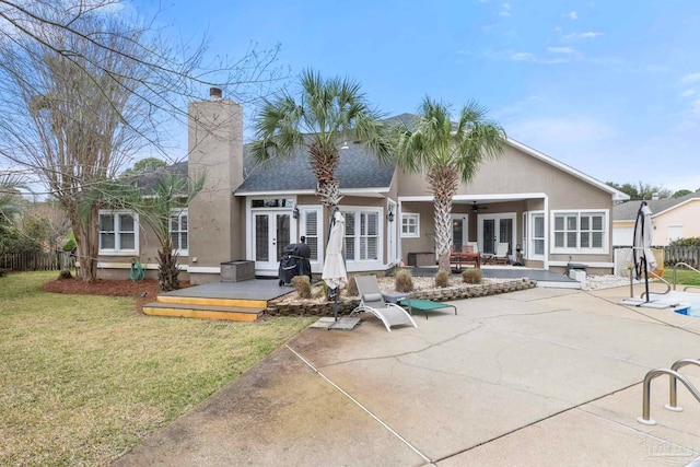 back of property with ceiling fan, french doors, a lawn, and stucco siding