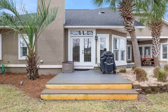 entrance to property featuring french doors, roof with shingles, a deck, and stucco siding