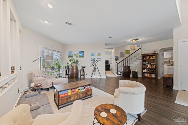 living room featuring visible vents, stairway, baseboards, and wood finished floors