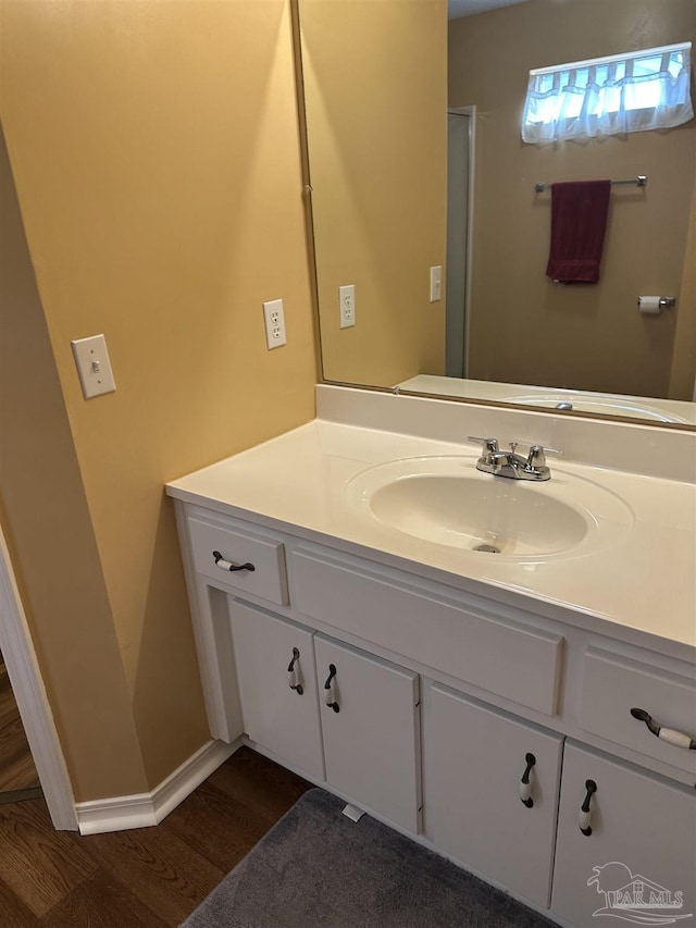 bathroom featuring baseboards, wood finished floors, and vanity