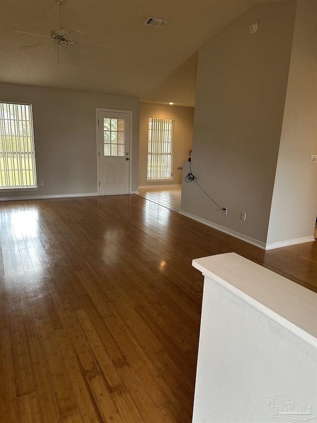 unfurnished living room featuring visible vents, ceiling fan, baseboards, and hardwood / wood-style flooring