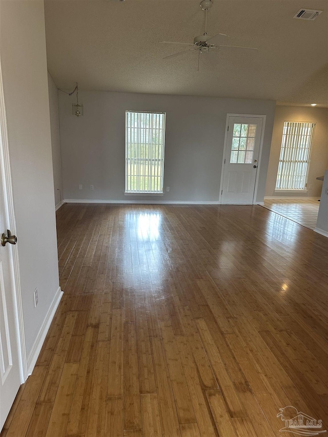 empty room featuring visible vents, ceiling fan, baseboards, and wood finished floors