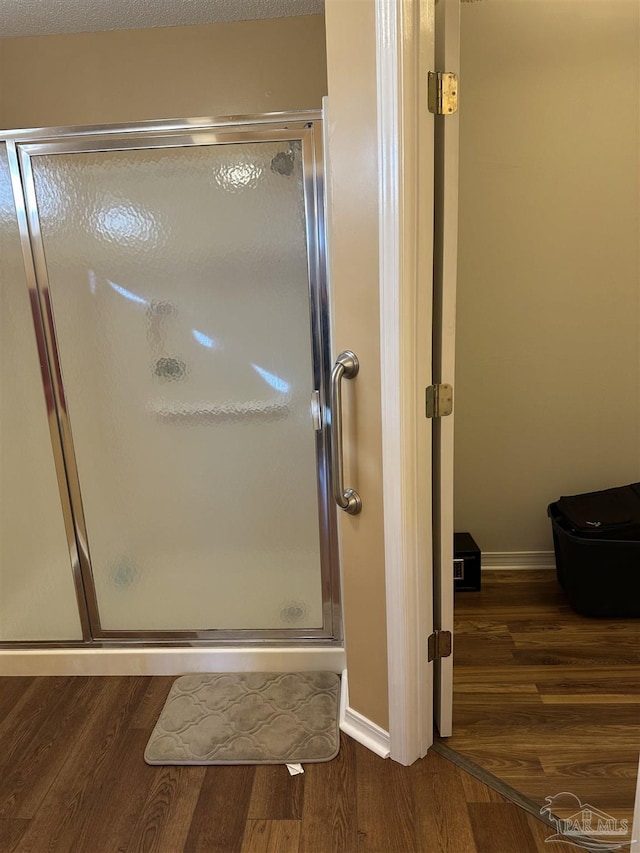 bathroom with a shower stall, baseboards, and wood finished floors