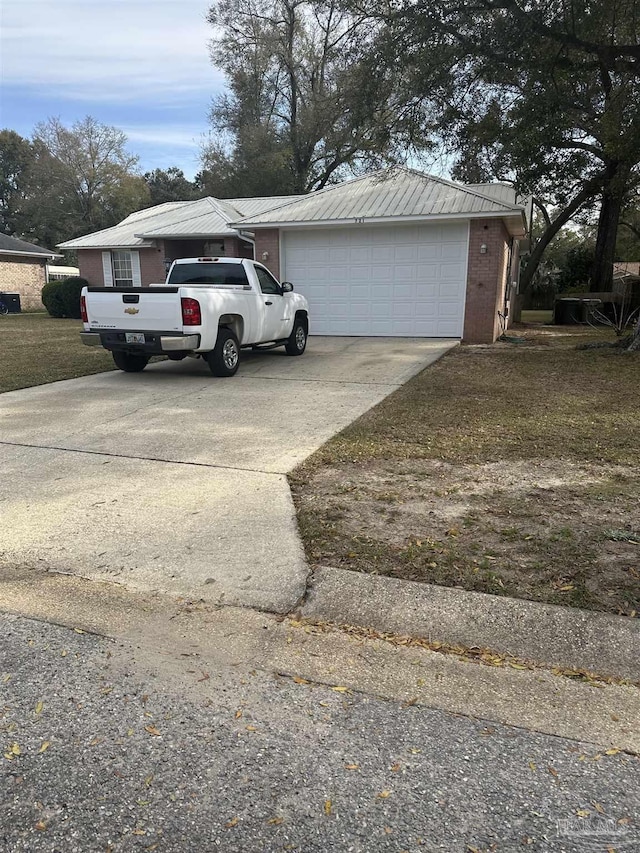 exterior space with driveway, an attached garage, metal roof, and brick siding