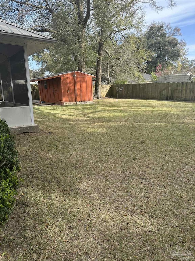 view of yard featuring an outbuilding, a shed, fence, and a sunroom