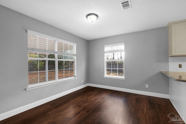 unfurnished dining area featuring dark wood-type flooring and a textured ceiling