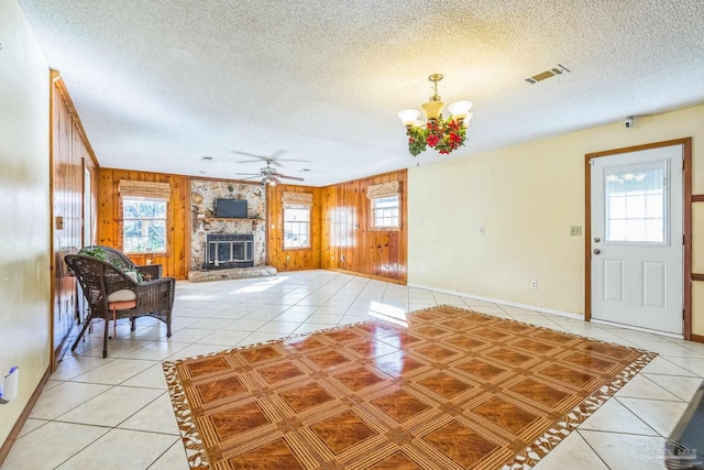 living room featuring wooden walls, ceiling fan with notable chandelier, and a wealth of natural light