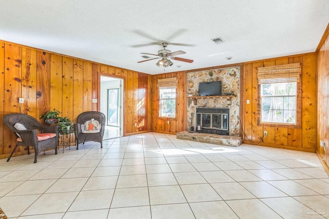 unfurnished living room with light tile patterned floors, a textured ceiling, ceiling fan, and wood walls