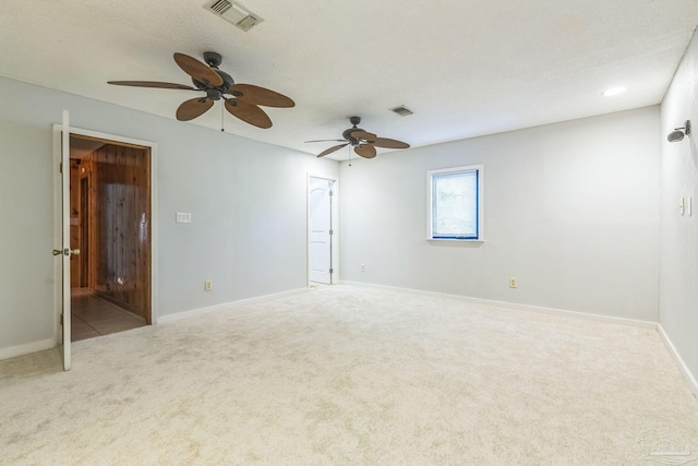 spare room with ceiling fan, light colored carpet, and a textured ceiling