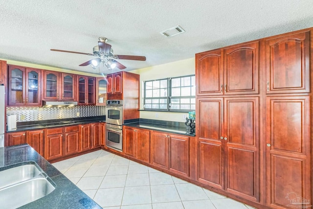 kitchen featuring a textured ceiling, light tile patterned floors, stainless steel appliances, and tasteful backsplash