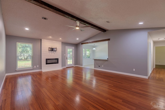 unfurnished living room with hardwood / wood-style flooring, plenty of natural light, a large fireplace, and a textured ceiling