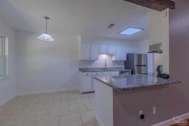 kitchen featuring sink, stainless steel refrigerator, white cabinetry, decorative light fixtures, and kitchen peninsula