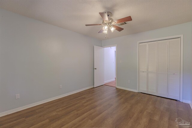 unfurnished bedroom with hardwood / wood-style flooring, a textured ceiling, a closet, and ceiling fan