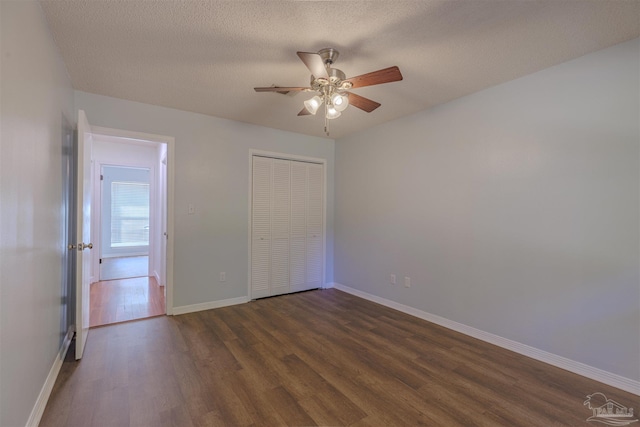 unfurnished bedroom with dark wood-type flooring, ceiling fan, a closet, and a textured ceiling