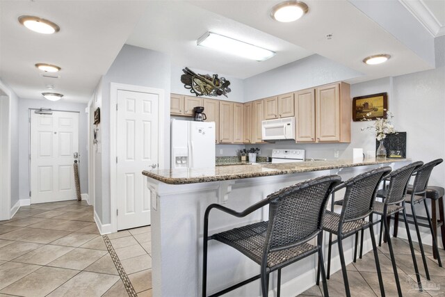 154 Ethel Wingate Dr Unit 109, Pensacola, FL 32507 - kitchen with kitchen peninsula, white appliances, light stone counters, light brown cabinetry, and a kitchen breakfast bar