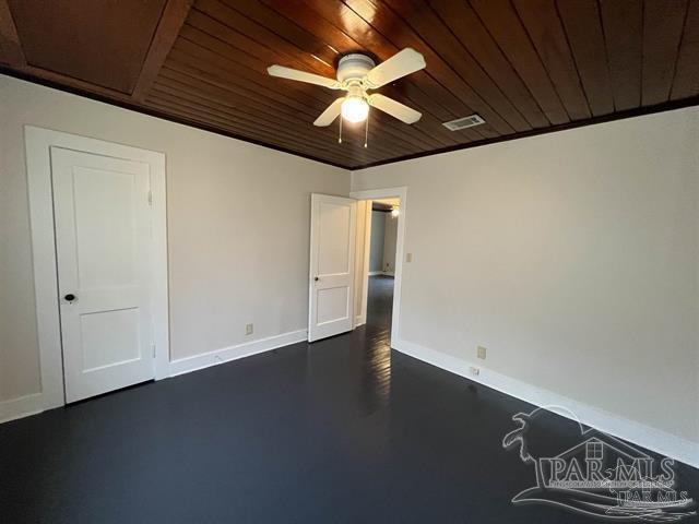 spare room with visible vents, finished concrete floors, ceiling fan, wooden ceiling, and baseboards