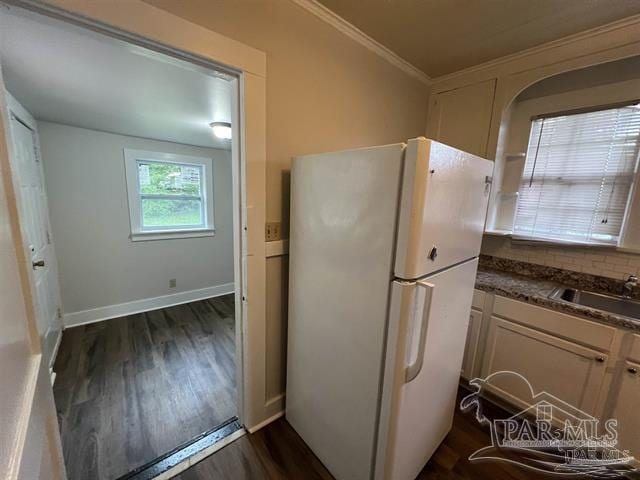 kitchen featuring dark wood-type flooring, a sink, freestanding refrigerator, dark countertops, and crown molding