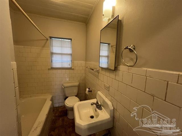 full bathroom featuring wainscoting, a sink, toilet, and tile walls