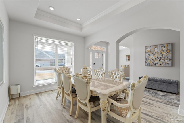 dining room with light hardwood / wood-style flooring, ornamental molding, and a raised ceiling