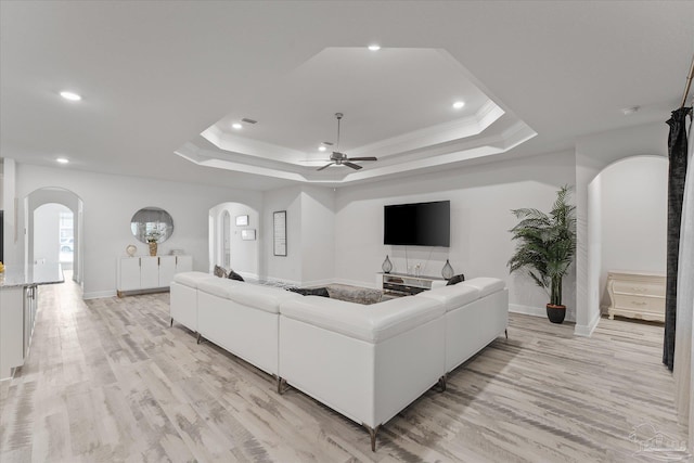 living room featuring crown molding, a tray ceiling, and light wood-type flooring