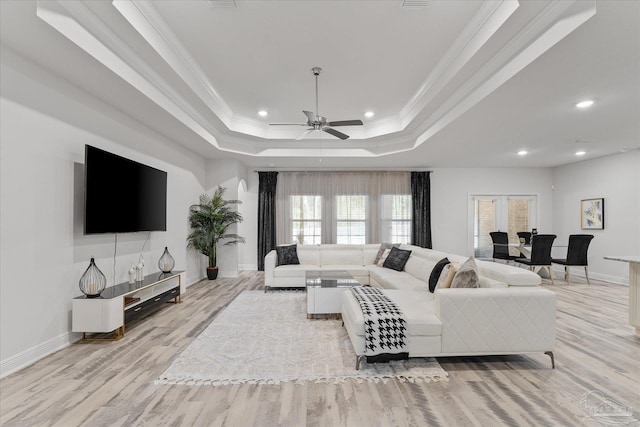 living room featuring crown molding, a healthy amount of sunlight, and a tray ceiling