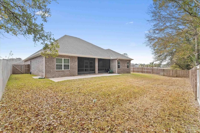 rear view of property featuring a patio area, a sunroom, and a lawn