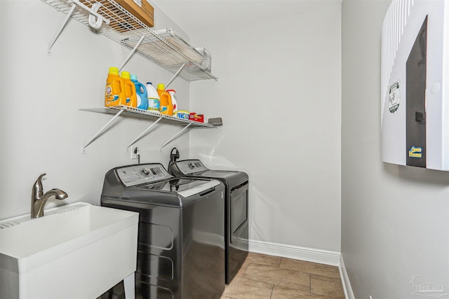 clothes washing area featuring laundry area, tile patterned flooring, baseboards, a sink, and independent washer and dryer