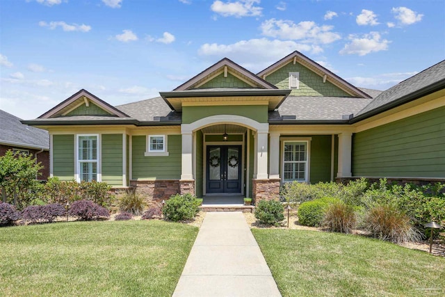 view of front facade featuring a shingled roof, french doors, and a front yard
