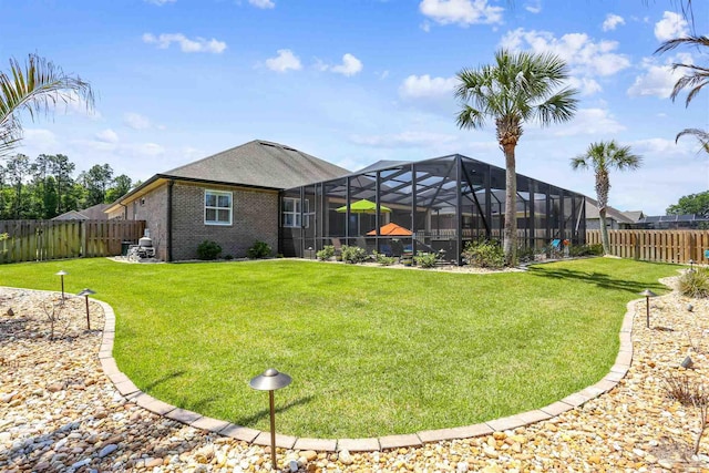 exterior space with a lawn, brick siding, a lanai, and a fenced backyard