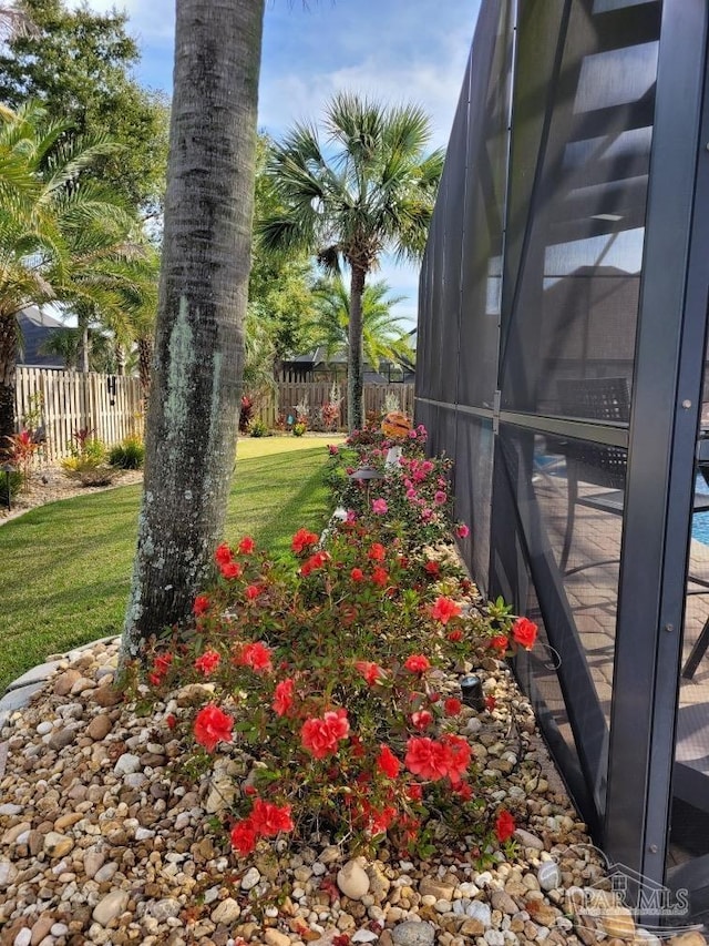 view of yard with glass enclosure and fence