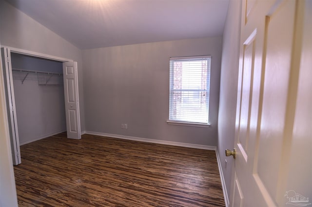 unfurnished bedroom with vaulted ceiling, a closet, and dark hardwood / wood-style floors