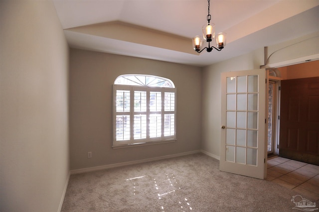 unfurnished room with light carpet, a tray ceiling, and an inviting chandelier