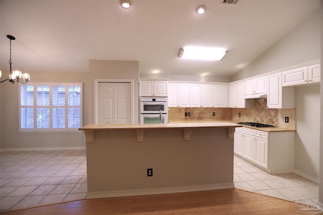 kitchen with hanging light fixtures, a kitchen island, a chandelier, light hardwood / wood-style floors, and white cabinets