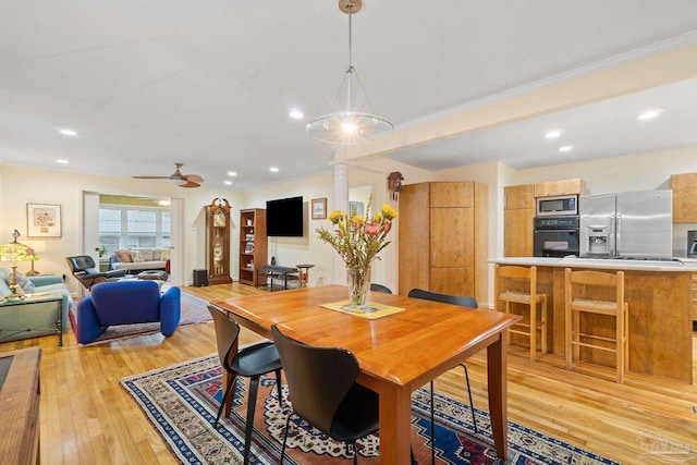 dining room with ceiling fan, light wood-type flooring, and crown molding