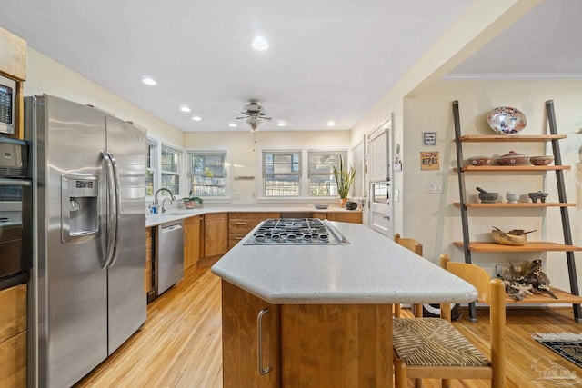 kitchen featuring sink, ceiling fan, light wood-type flooring, ornamental molding, and appliances with stainless steel finishes