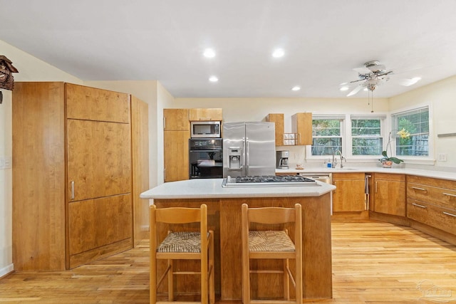 kitchen featuring sink, light hardwood / wood-style flooring, a kitchen island, a kitchen bar, and stainless steel appliances