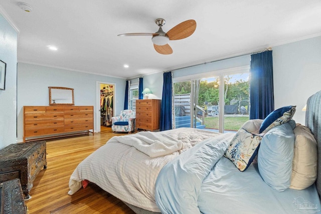 bedroom with a spacious closet, ceiling fan, light hardwood / wood-style floors, a closet, and ornamental molding