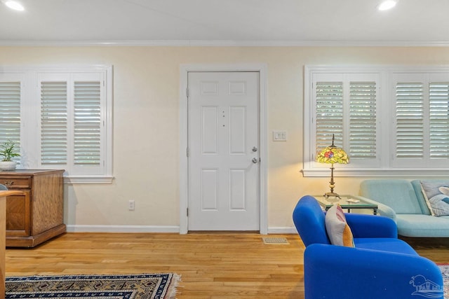 foyer with crown molding, plenty of natural light, and wood-type flooring