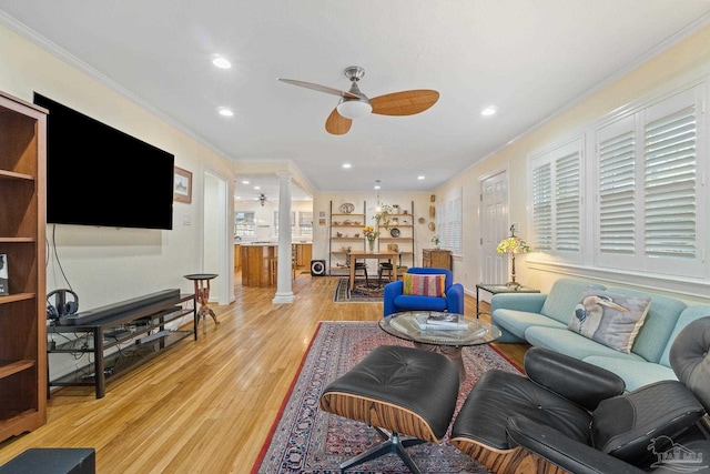 living room with ceiling fan, decorative columns, ornamental molding, and light hardwood / wood-style flooring