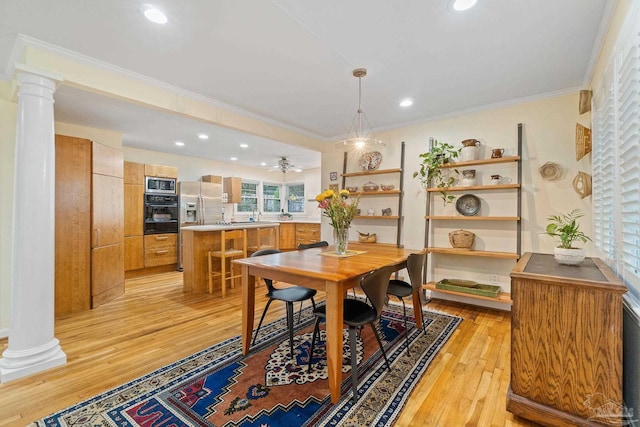 dining room featuring sink, crown molding, ceiling fan, light wood-type flooring, and ornate columns