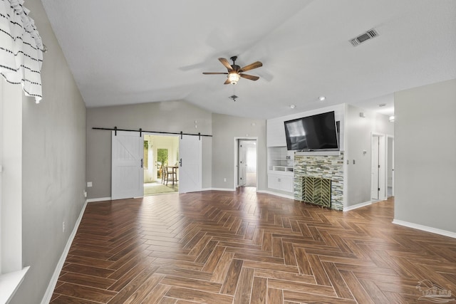 unfurnished living room featuring a barn door, a ceiling fan, visible vents, baseboards, and lofted ceiling
