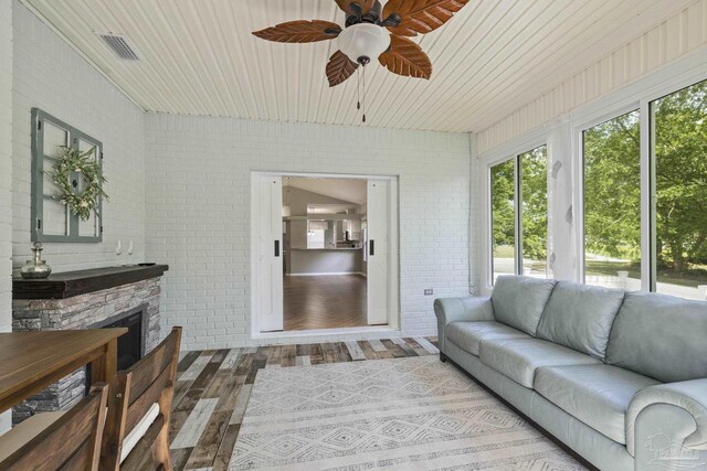 sunroom / solarium featuring visible vents, wood finished floors, and brick wall