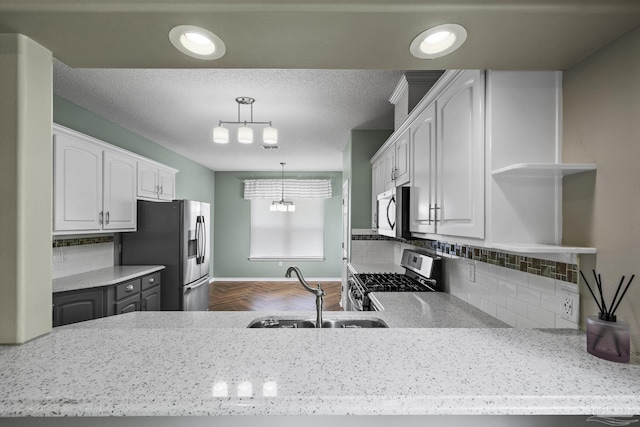 kitchen featuring open shelves, appliances with stainless steel finishes, backsplash, a sink, and a textured ceiling
