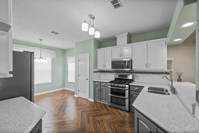kitchen featuring a sink, stainless steel appliances, visible vents, baseboards, and white cabinets